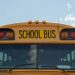 School bus with bold black lettering against a blue sky