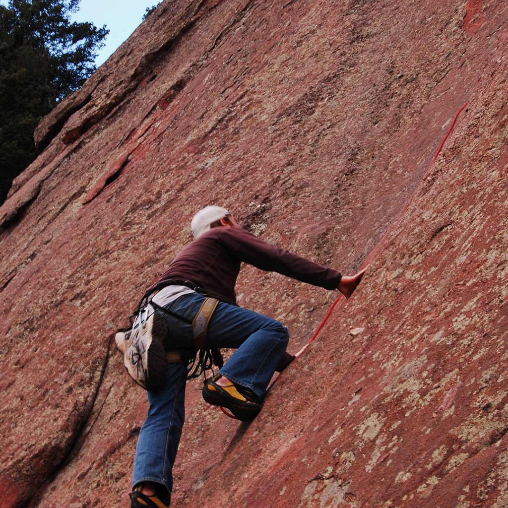 Rock climber scaling the red sandstone Flatirons in Boulder