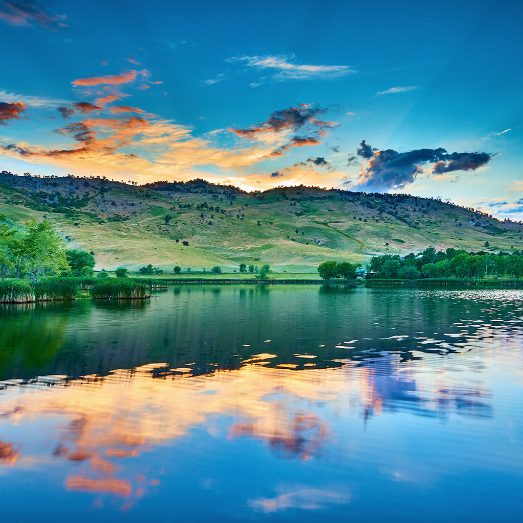 Lake with hillside and colorful sunset reflection