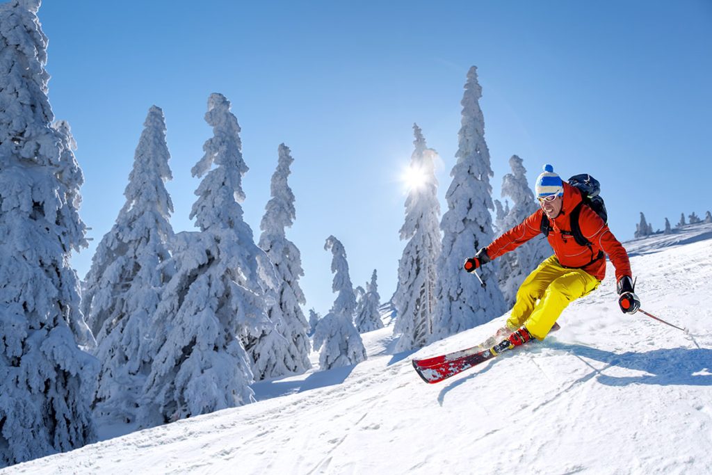 Skier descending snowy slope on sunny day