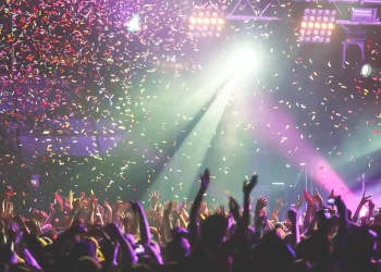 Crowd enjoying a live concert with colorful confetti and stage lights.