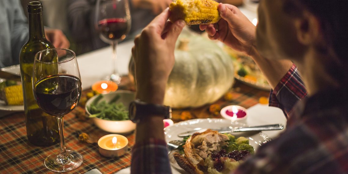 Man eating corn at table on Thanksgiving