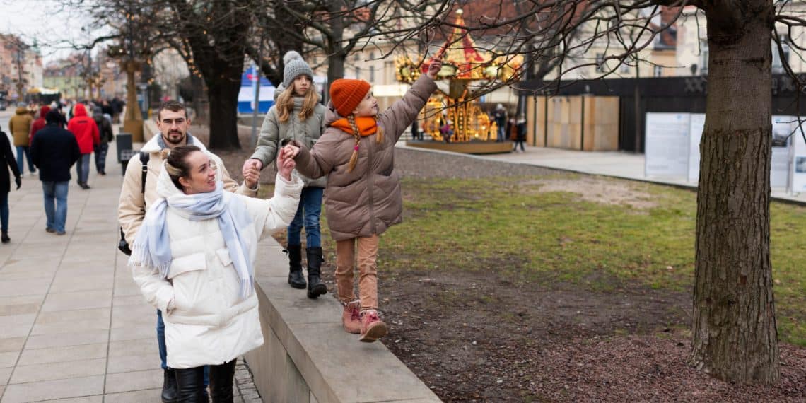 A family walks together in a city park during winter