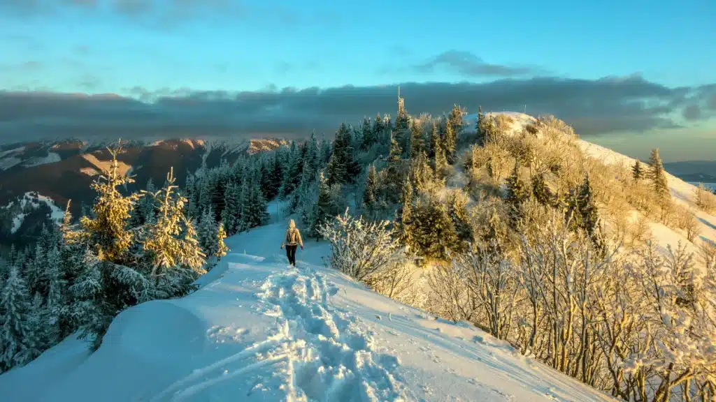 Hiker on snowy mountain ridge at sunset