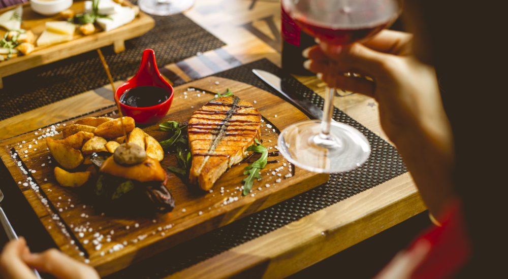 side view salmon steak with potato in a rural pomegranate sauce salt and glass of wine on the table